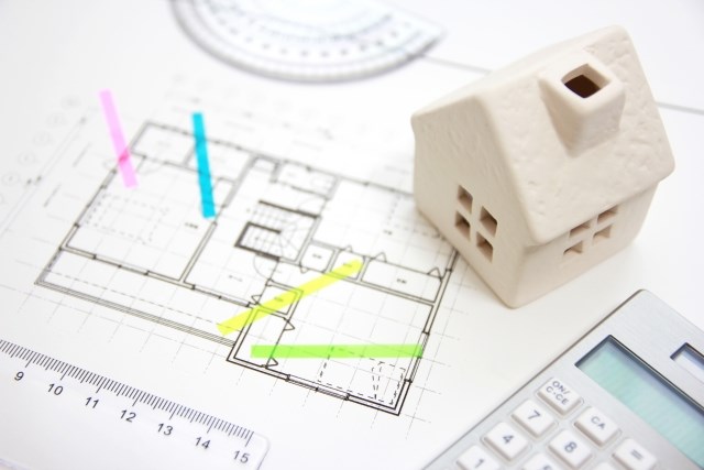 家の模型と設計図と電卓